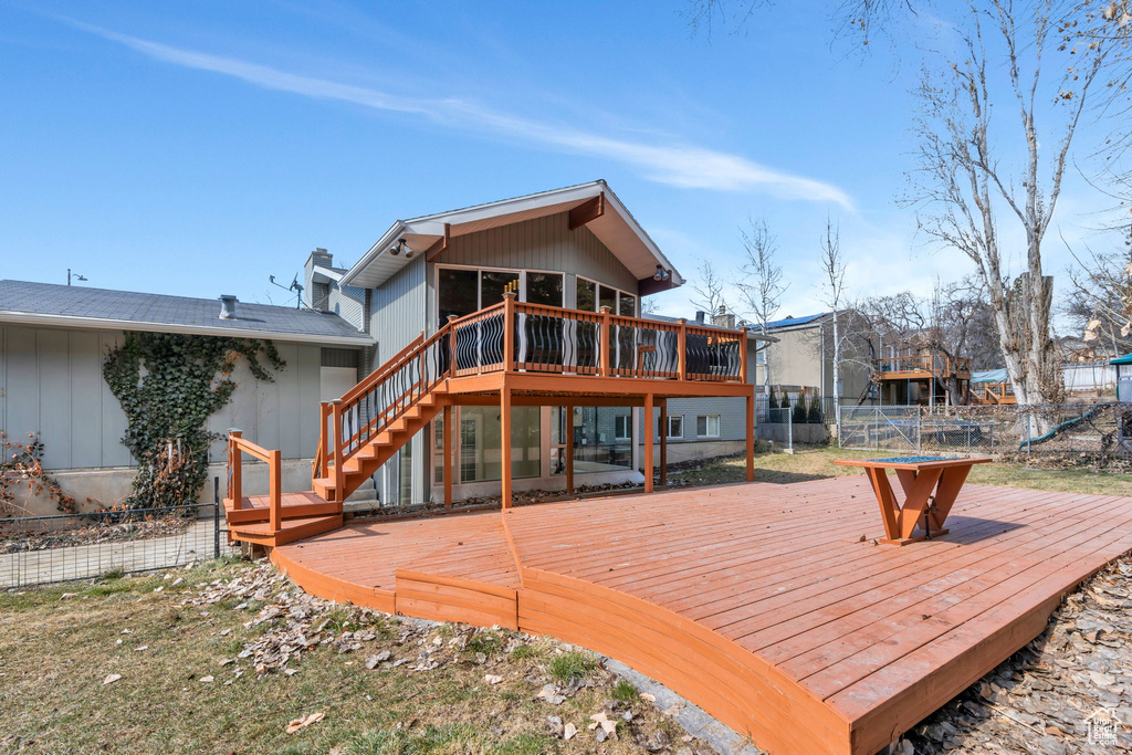 Rear view of property featuring fence, a wooden deck, and stairs