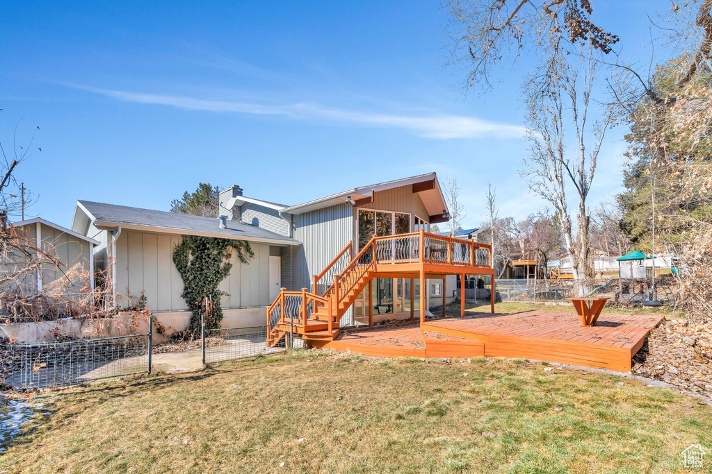 Back of house featuring a lawn, stairway, a wooden deck, and fence