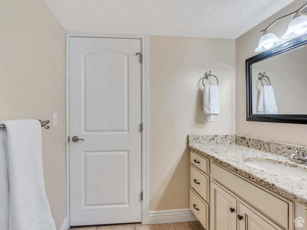 Bathroom featuring a textured ceiling, vanity, and baseboards