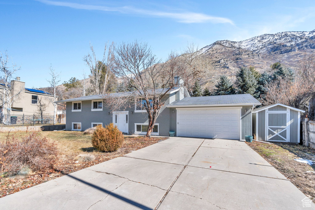 View of front facade featuring driveway, an attached garage, fence, and a mountain view