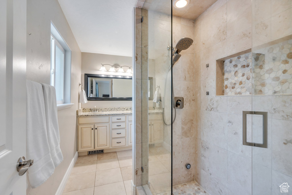 Full bathroom with a stall shower, visible vents, baseboards, tile patterned floors, and vanity