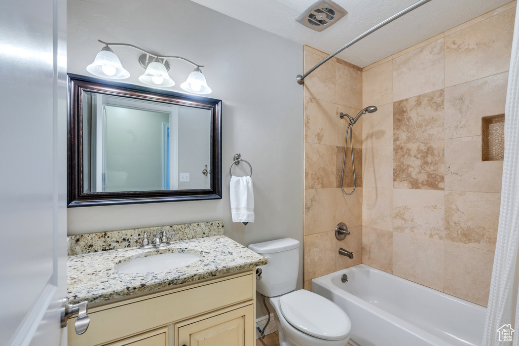 Bathroom with toilet, shower / bath combo with shower curtain, and vanity