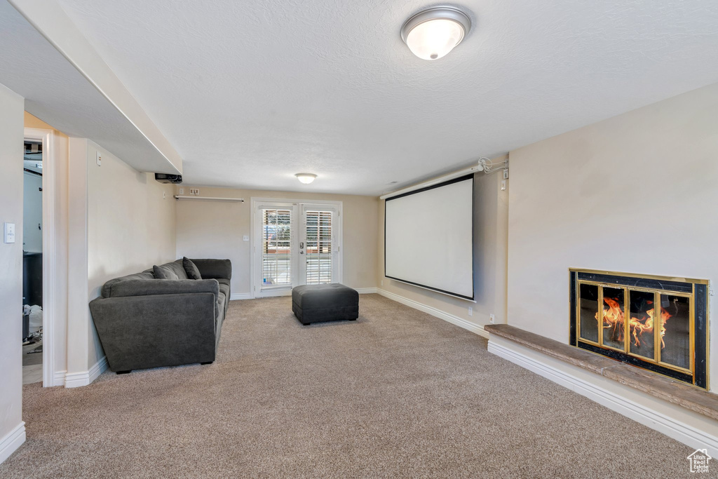 Carpeted cinema room with a glass covered fireplace, a textured ceiling, and baseboards