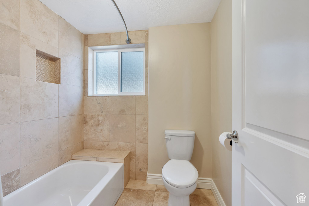 Full bathroom featuring a bathtub, tile patterned flooring, baseboards, and toilet