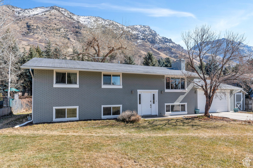 Split foyer home with an attached garage, driveway, a front yard, and a mountain view