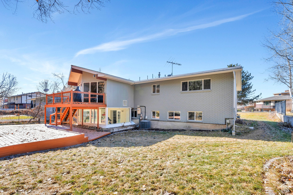 Back of house with stairway, brick siding, a lawn, and a deck