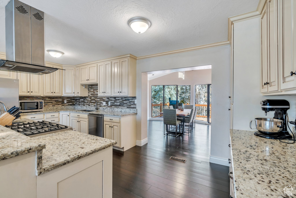 Kitchen with light stone counters, cream cabinets, visible vents, appliances with stainless steel finishes, and decorative backsplash