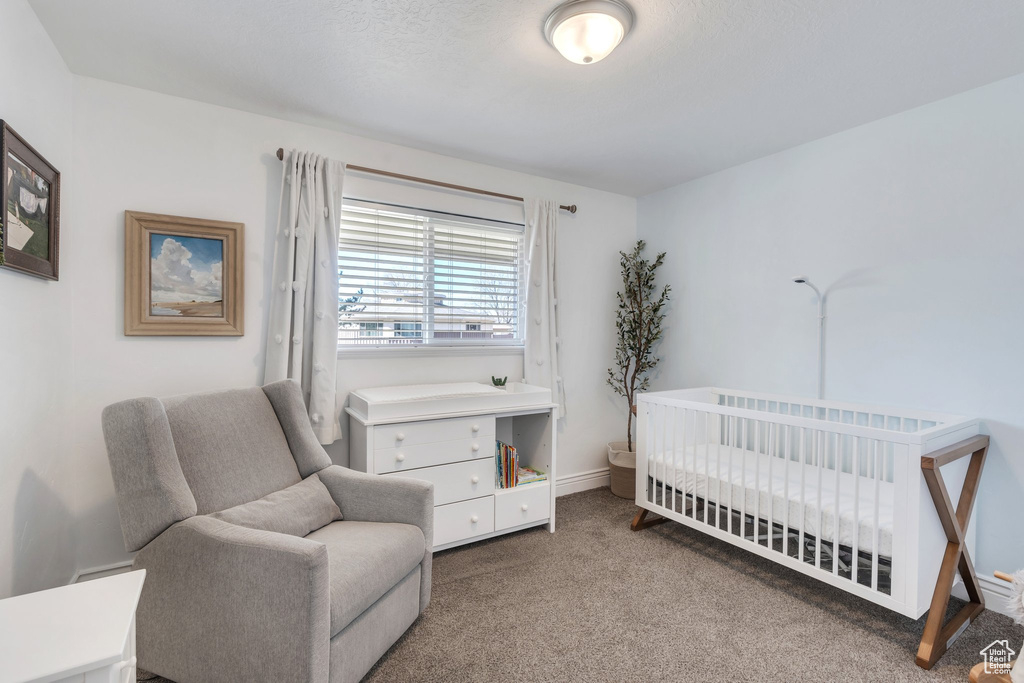 Carpeted bedroom featuring a crib and baseboards