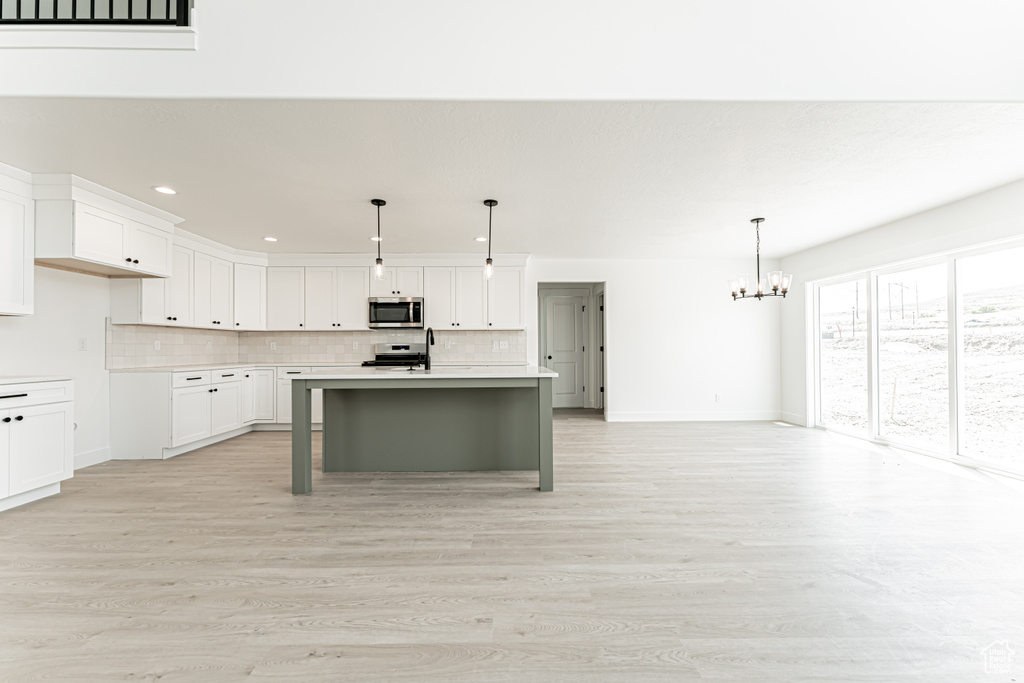 Kitchen featuring stainless steel appliances, a chandelier, tasteful backsplash, light countertops, and recessed lighting