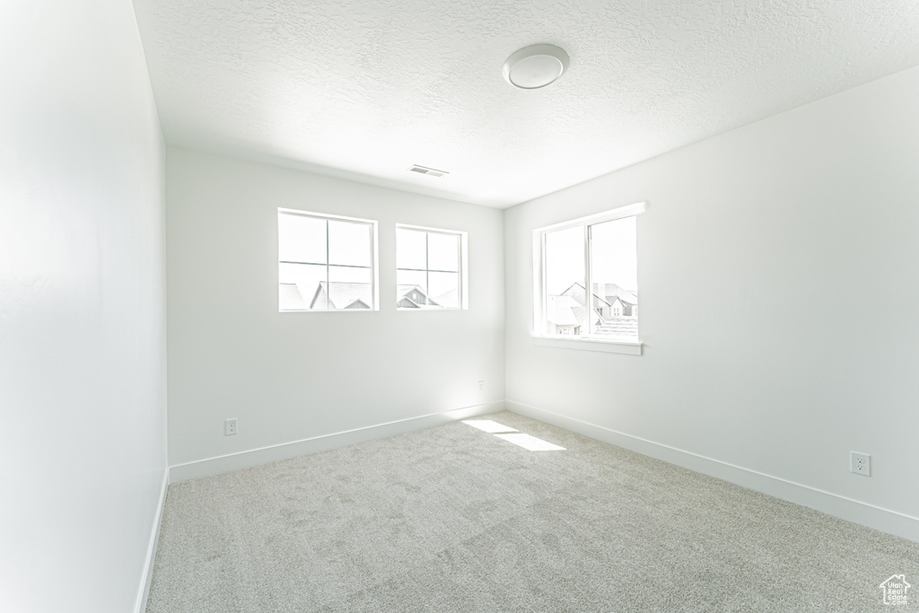 Carpeted spare room with baseboards and a textured ceiling