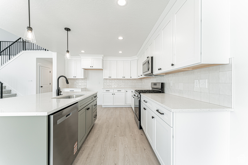 Kitchen featuring stainless steel appliances, a sink, light wood-type flooring, white cabinets, and recessed lighting