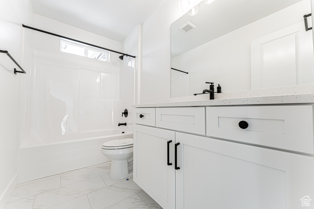 Full bath with vanity, bathtub / shower combination, toilet, and marble look tile flooring
