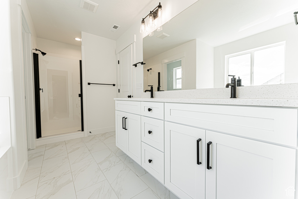 Full bath with a stall shower, double vanity, marble look tiles, healthy amount of natural light, and recessed lighting