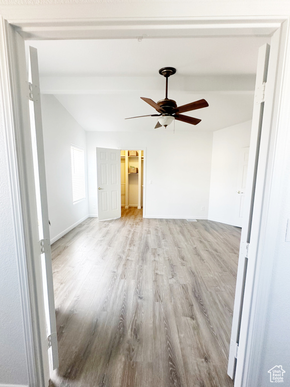 Empty room with vaulted ceiling with beams, light wood-type flooring, baseboards, and ceiling fan