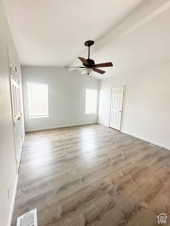 Unfurnished room featuring lofted ceiling, visible vents, baseboards, and wood finished floors