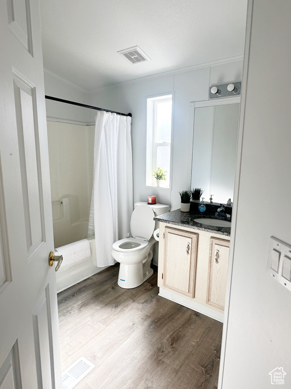 Bathroom with shower / tub combo with curtain, visible vents, toilet, vanity, and wood finished floors