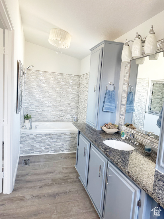 Full bathroom featuring tiled shower, tiled bath, wood finished floors, and vanity