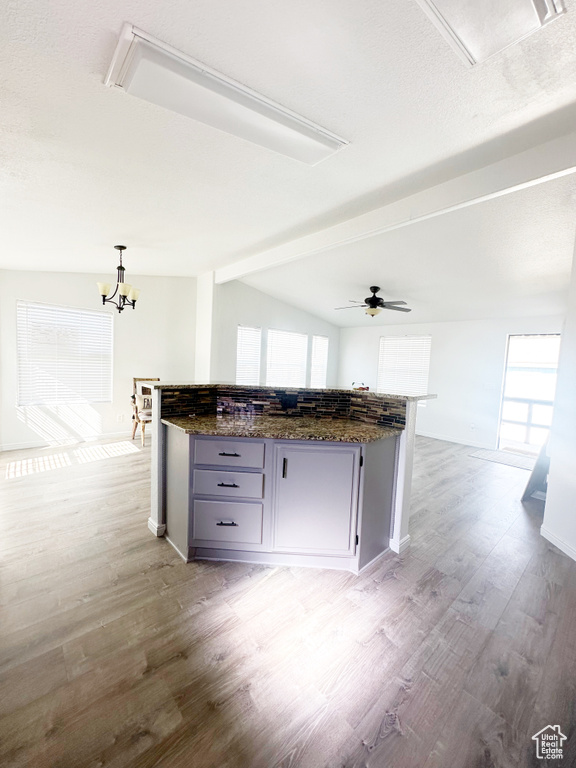 Kitchen with light wood-style floors, vaulted ceiling, gray cabinetry, and a kitchen island