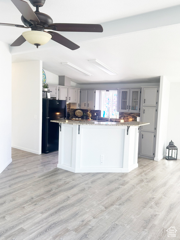 Kitchen with light wood-style floors, gray cabinets, a kitchen breakfast bar, and freestanding refrigerator