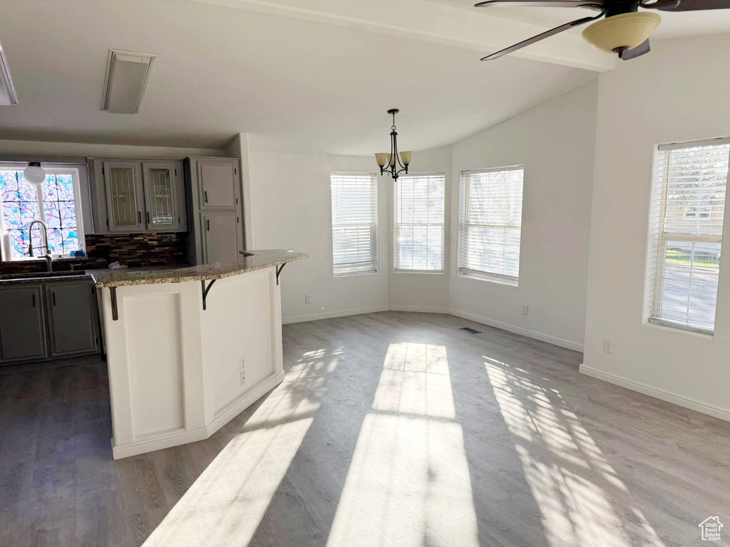 Kitchen with vaulted ceiling, a breakfast bar, plenty of natural light, and a sink