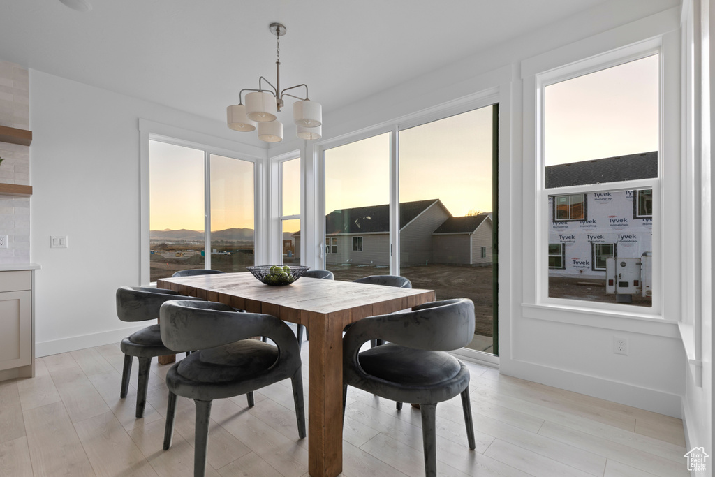 Dining space featuring a healthy amount of sunlight, light wood-style flooring, baseboards, and a notable chandelier