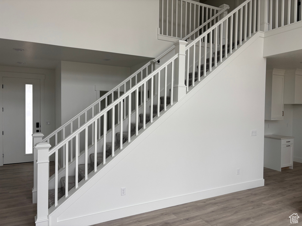 Staircase featuring wood finished floors, baseboards, and a towering ceiling