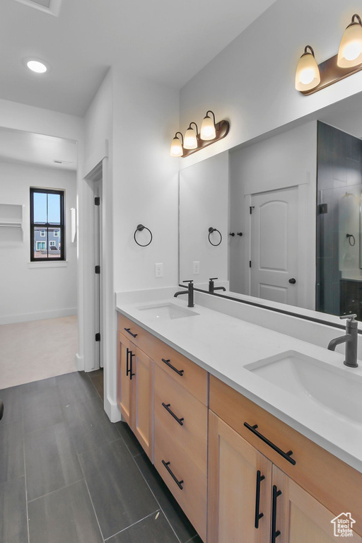 Bathroom featuring a sink, a shower stall, baseboards, and double vanity