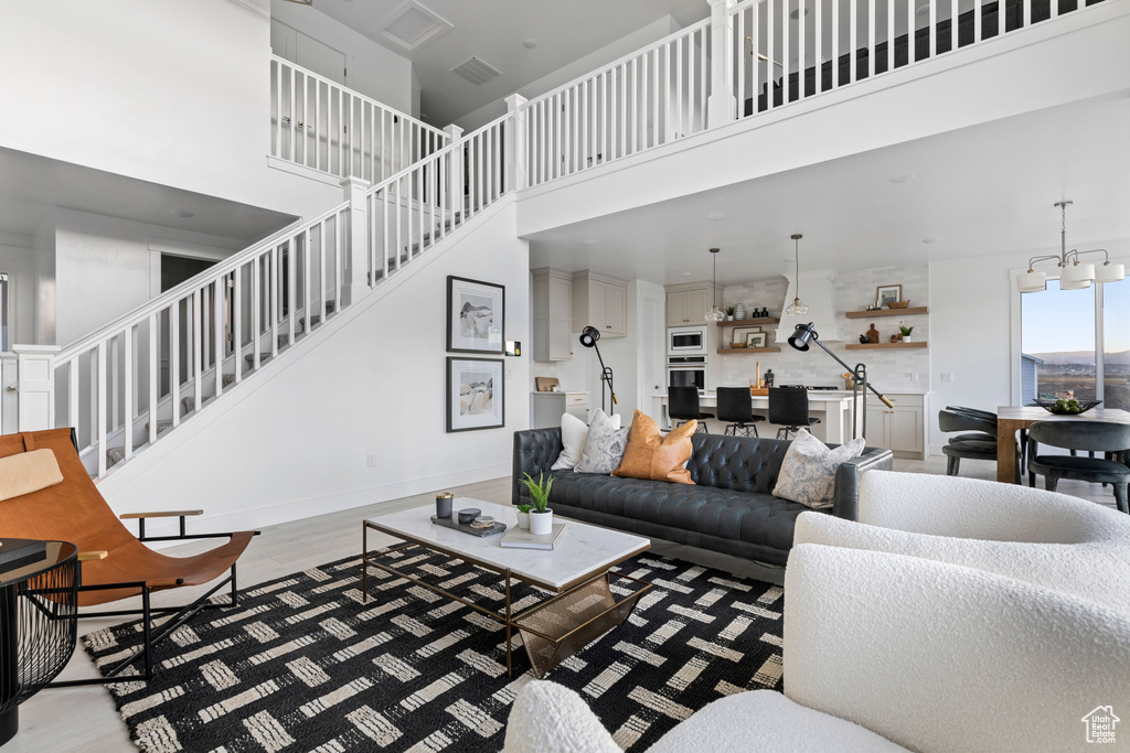 Living area with stairway, a towering ceiling, light wood-style flooring, and a notable chandelier