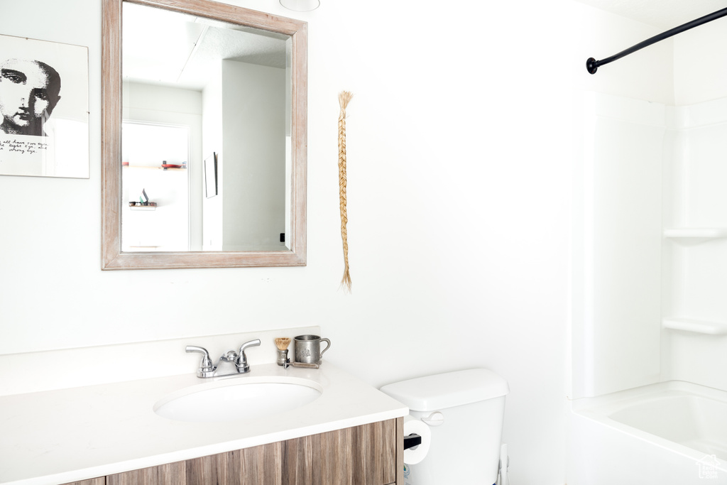Bathroom featuring shower / bath combination, vanity, and toilet