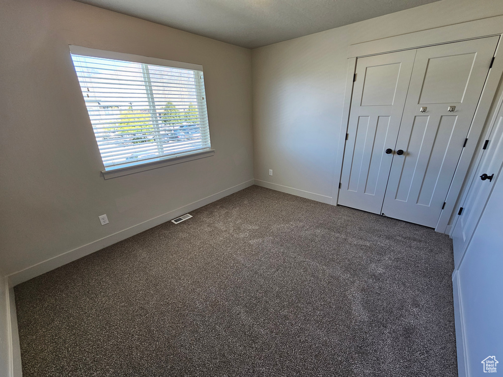 Unfurnished bedroom featuring a closet, carpet flooring, visible vents, and baseboards