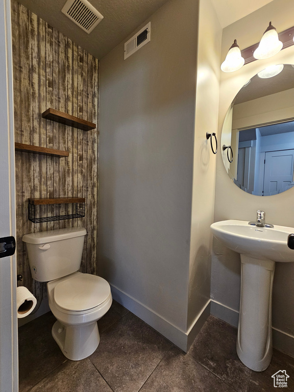 Half bath with toilet, visible vents, and baseboards