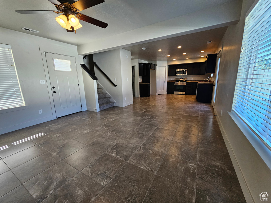 Unfurnished living room featuring a healthy amount of sunlight, baseboards, stairs, and visible vents