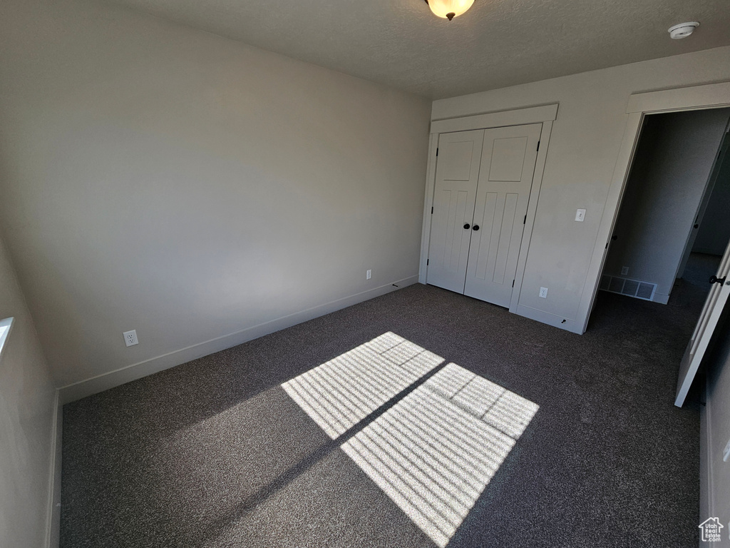 Unfurnished bedroom featuring a closet, a textured ceiling, and baseboards