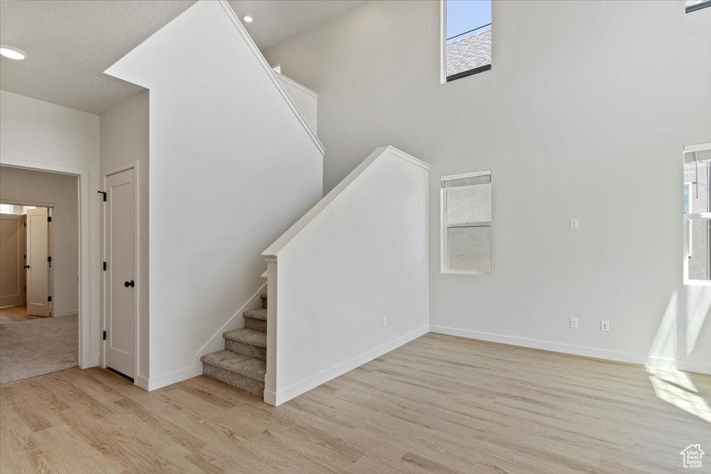 Staircase with wood finished floors, plenty of natural light, recessed lighting, and a towering ceiling