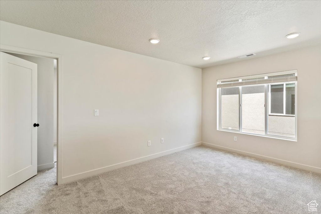 Spare room featuring light colored carpet, a textured ceiling, and recessed lighting
