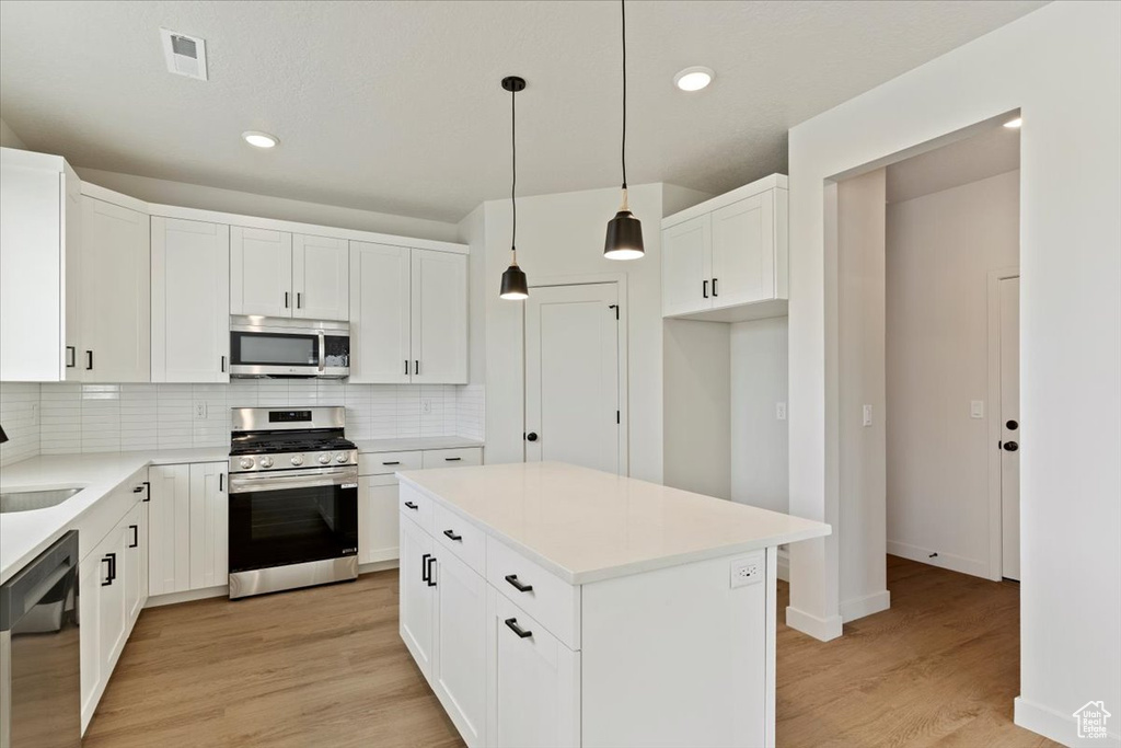 Kitchen with stainless steel appliances, tasteful backsplash, light wood-type flooring, recessed lighting, and white cabinets