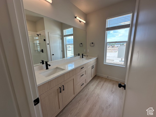 Bathroom featuring double vanity, a walk in shower, and wood finished floors