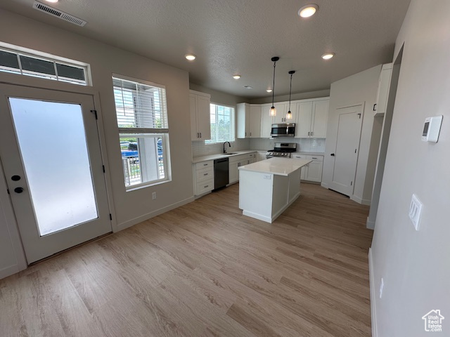 Kitchen featuring appliances with stainless steel finishes, white cabinetry, light wood-type flooring, light countertops, and recessed lighting