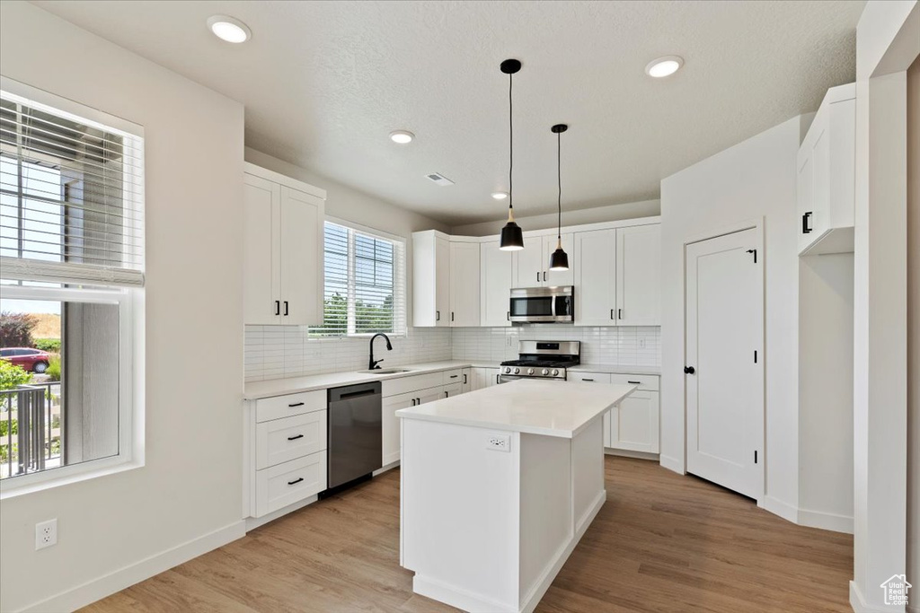 Kitchen with appliances with stainless steel finishes, backsplash, white cabinets, and recessed lighting