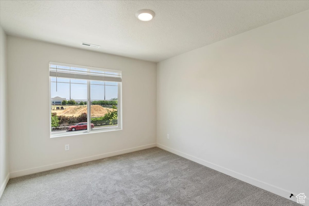 Carpeted spare room featuring baseboards
