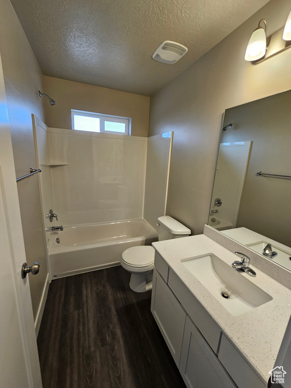 Full bath featuring visible vents, shower / bathing tub combination, toilet, a textured ceiling, and wood finished floors