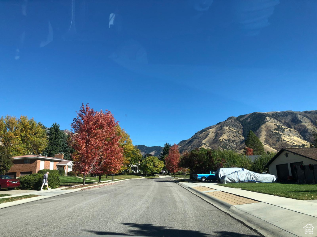 View of asphalt street featuring sidewalks, curbs, and a mountain view