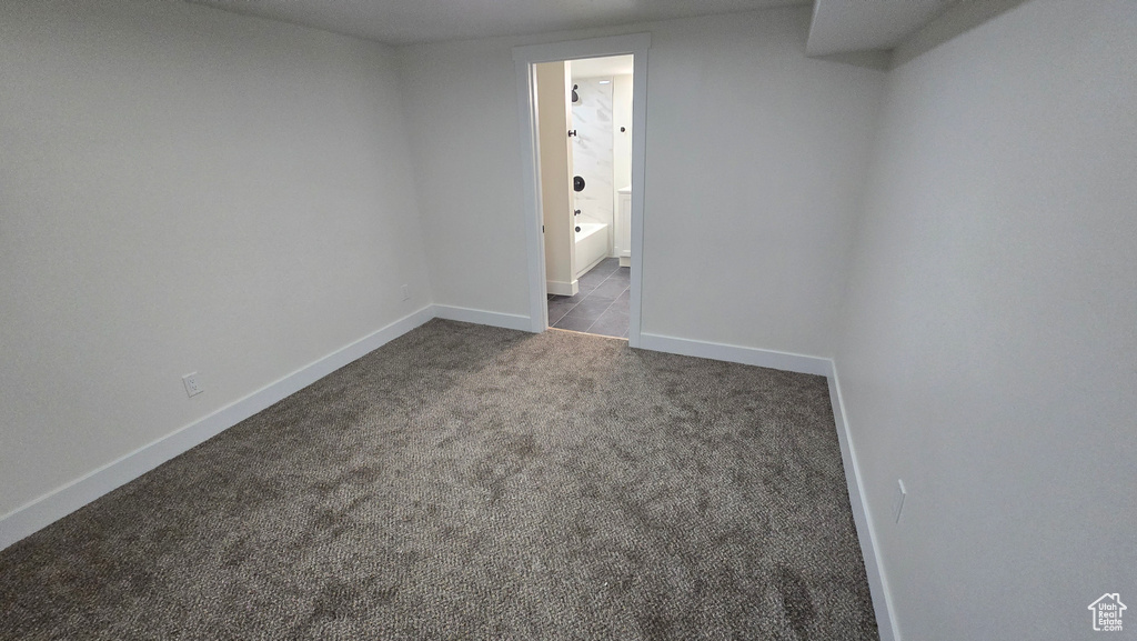 Spare room with dark colored carpet and baseboards