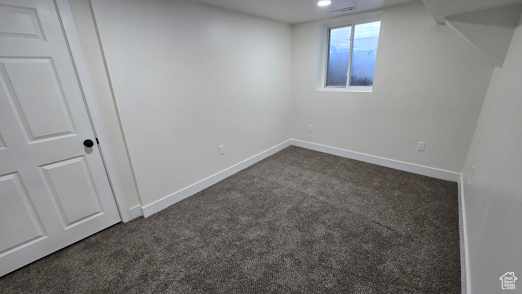 Basement featuring dark colored carpet, visible vents, and baseboards