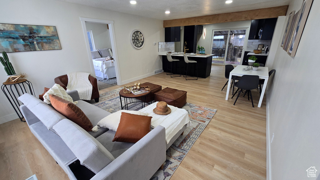 Living room with baseboards, light wood-style flooring, and recessed lighting