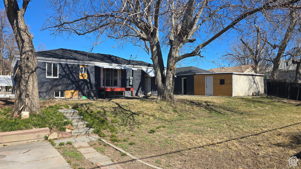 Back of property with a lawn and brick siding