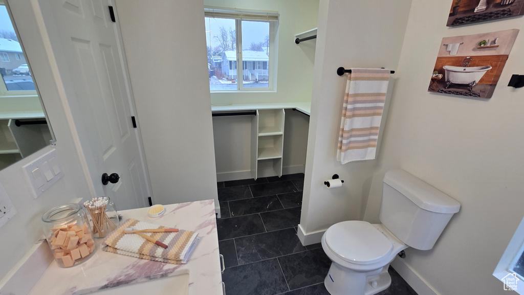 Bathroom featuring toilet, tile patterned flooring, and baseboards