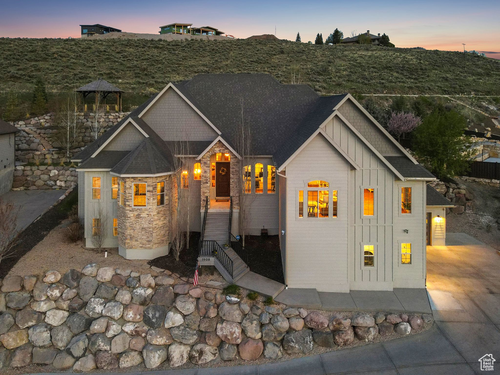 View of front facade featuring board and batten siding, driveway, and stone siding