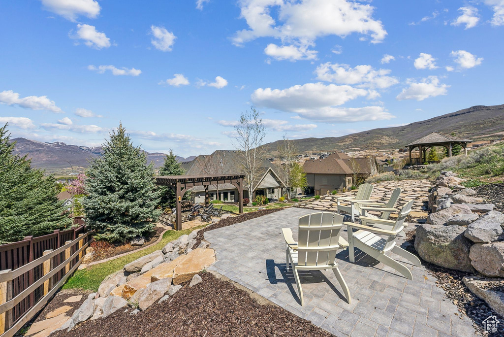 View of patio with a gazebo, a mountain view, a pergola, and fence