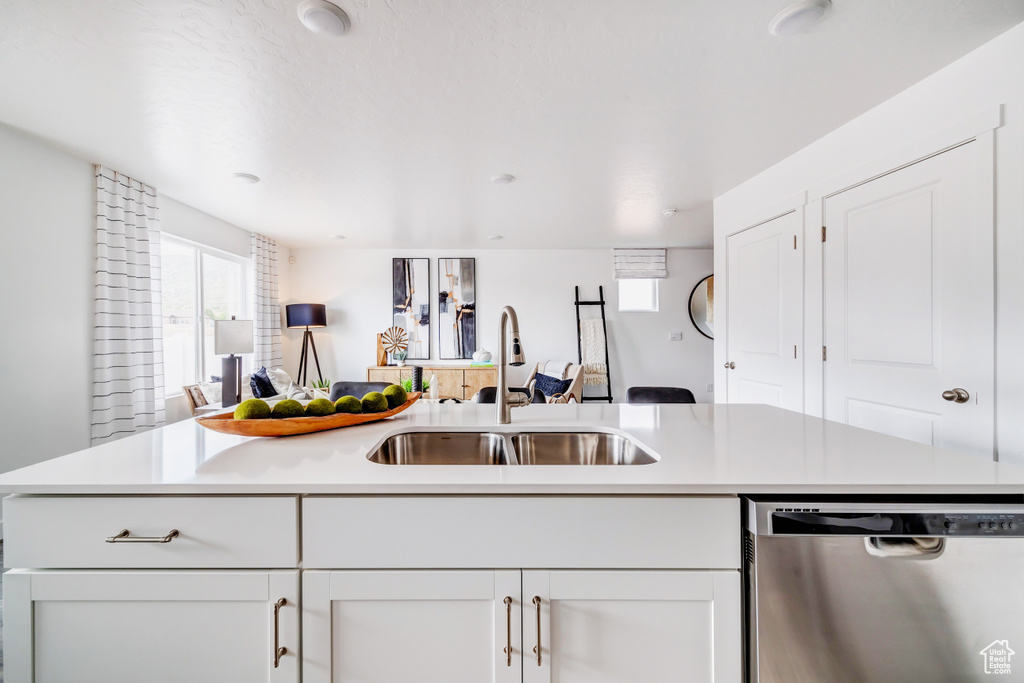 Kitchen featuring a sink, open floor plan, stainless steel dishwasher, and light countertops